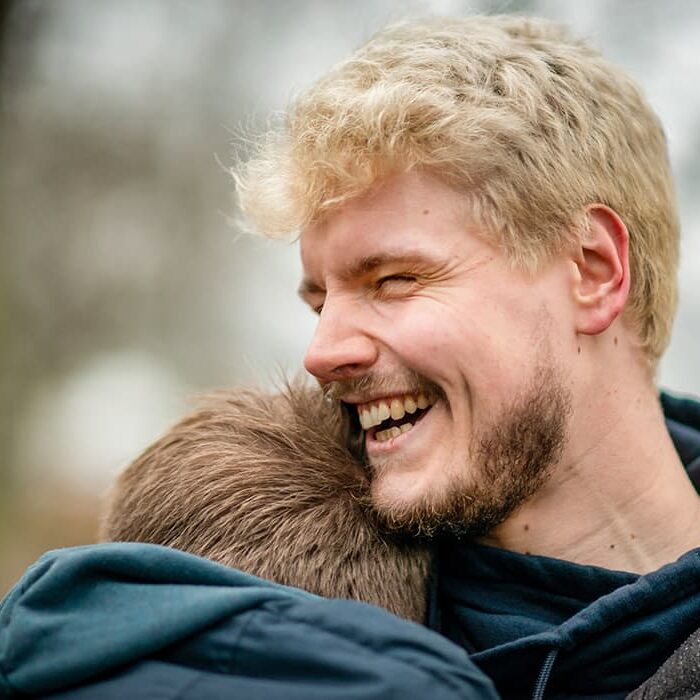 Two guys with blonde hair hugging and smiling