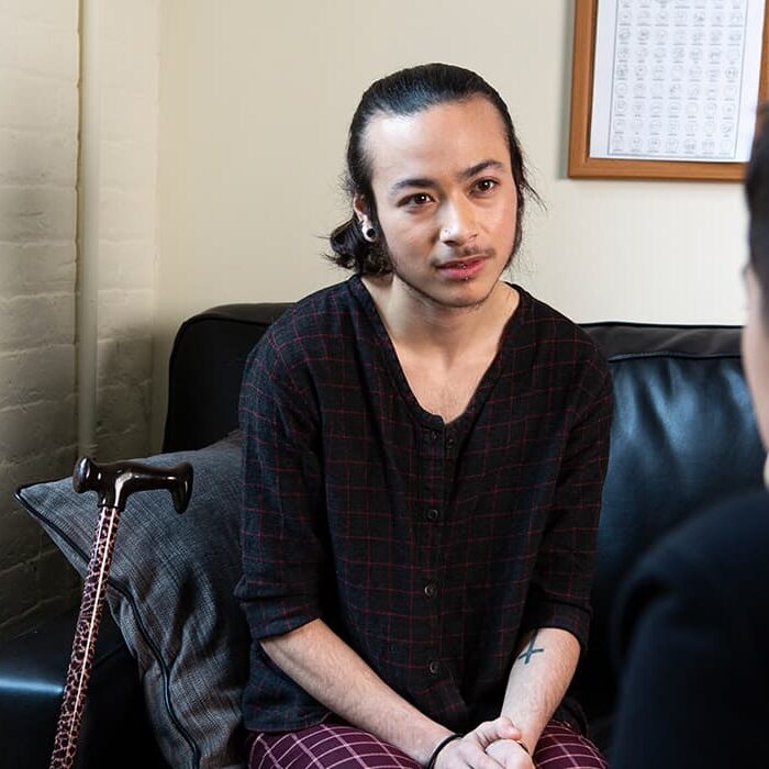 A person wearing a checkered black and red shirt listening to counsellor